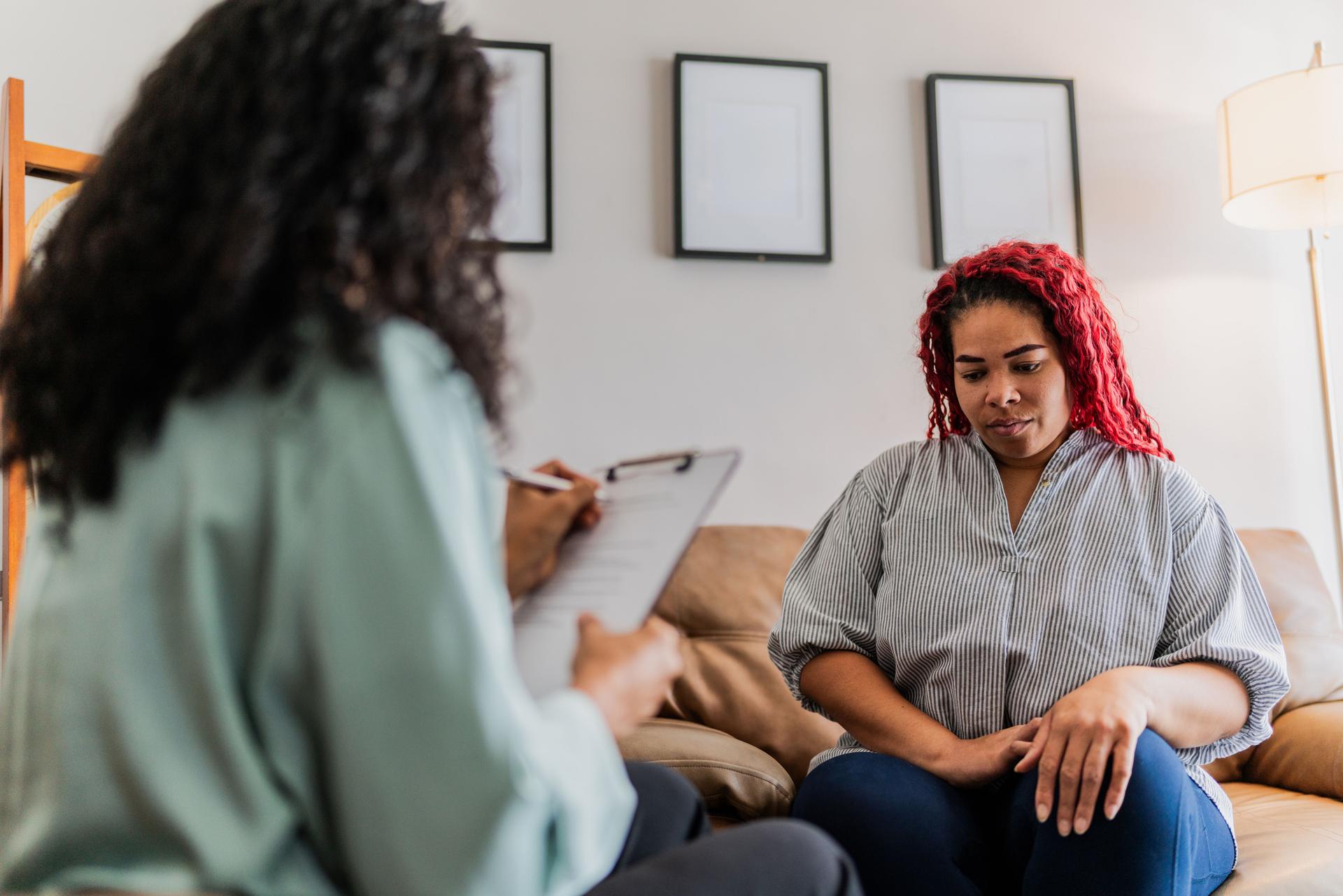 Mid adult patient woman talking with psychotherapist during therapy session at clinic