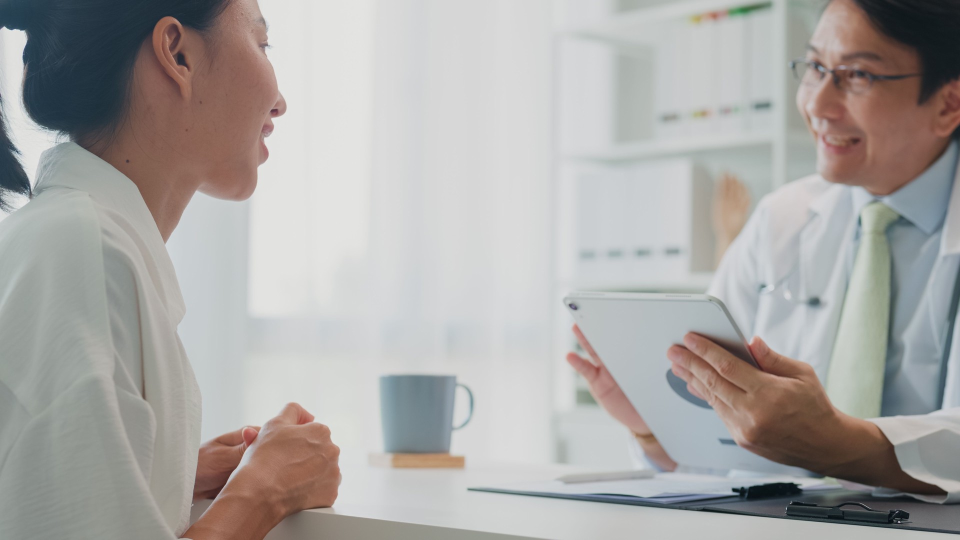 Adult Asian male doctors medical using tablet results during consultation with female patient in hospital. Medical health care.